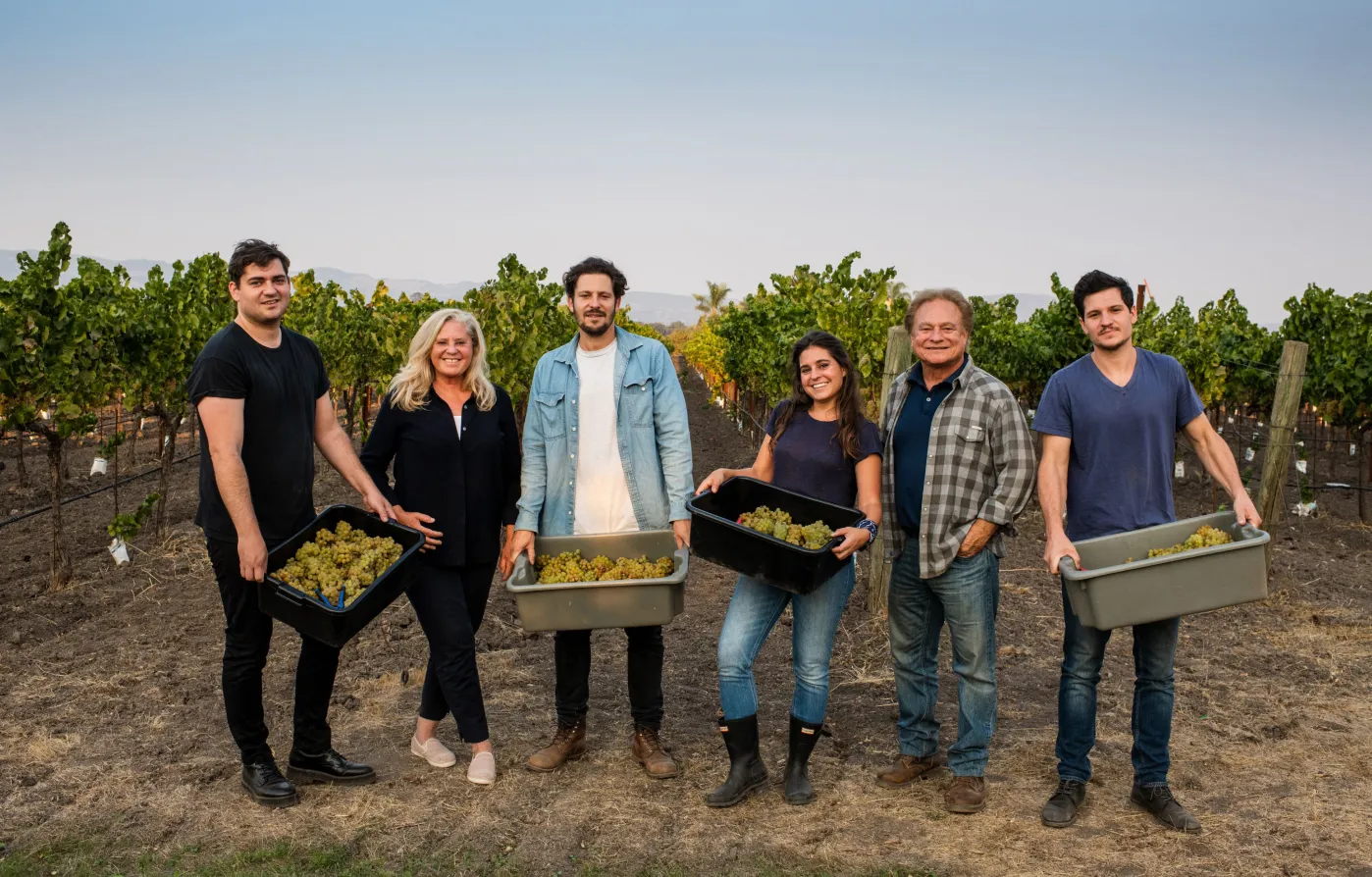 Hanson family members in vineyard holding buckets of grapes
