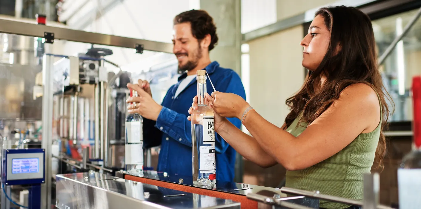 brandon and alanna hanson labelling bottles of vodka