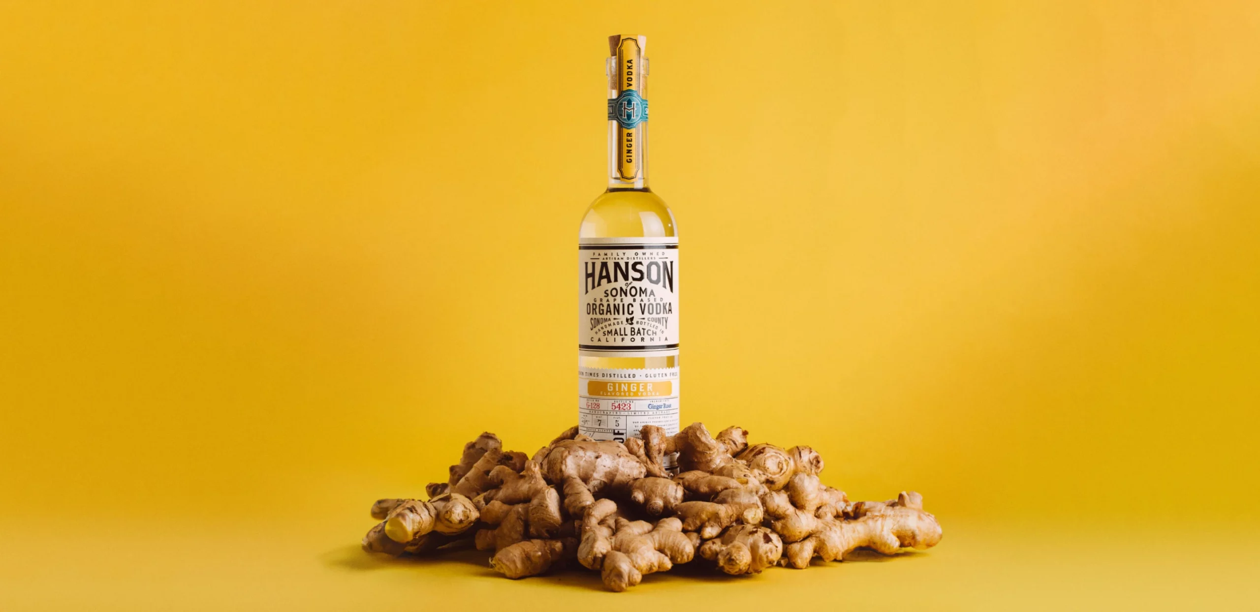 Hanson ginger vodka with ginger pieces on a yellow background, link to blog post article by Robb Report about the best bottles of premium vodka to buy right now