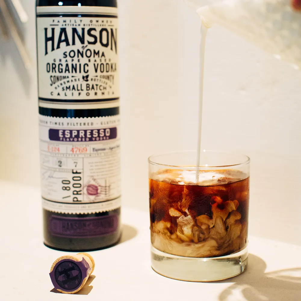 A White Russian cocktail next to a bottle of Hanson espresso vodka