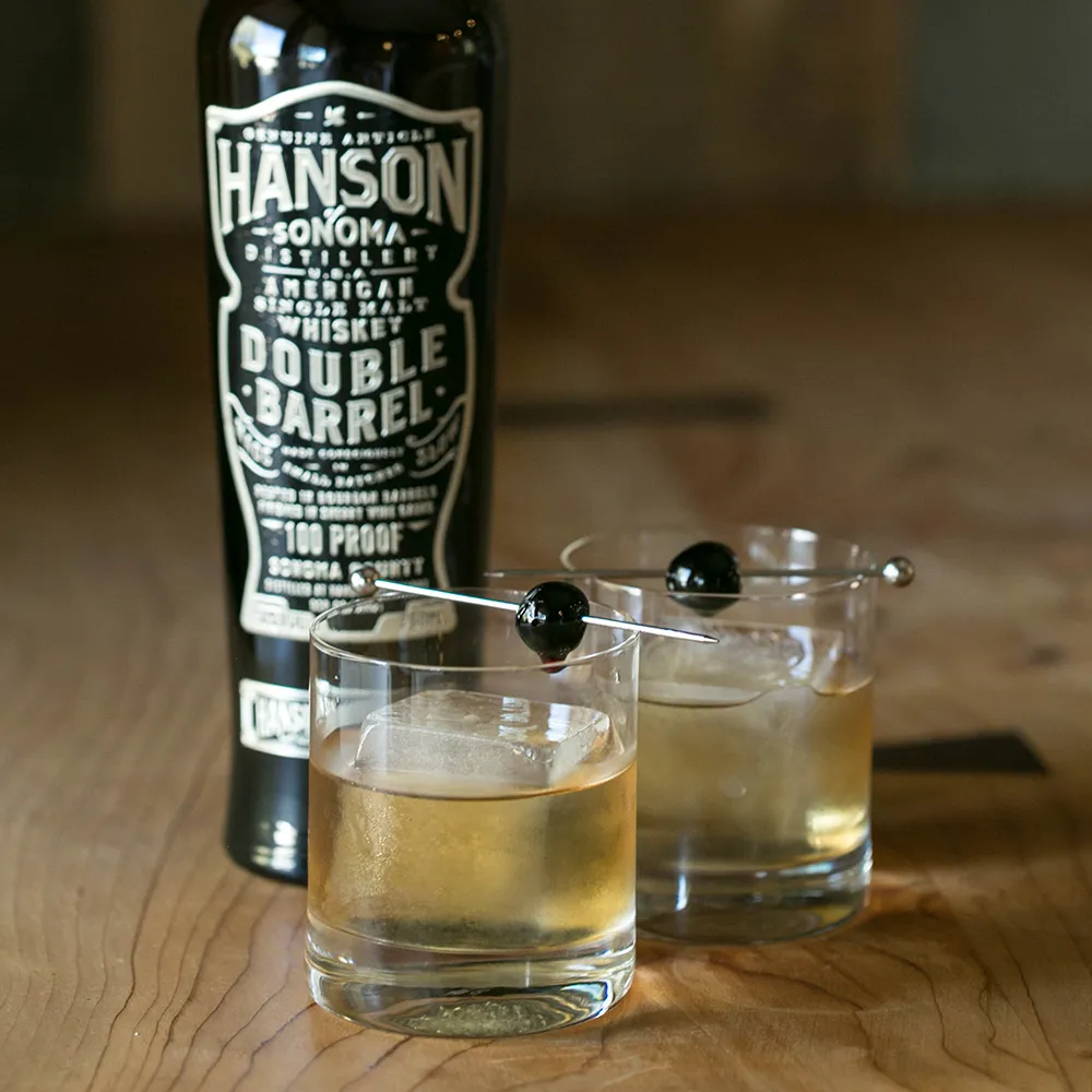 Some whiskey based cocktails next to a bottle of Hanson whiskey